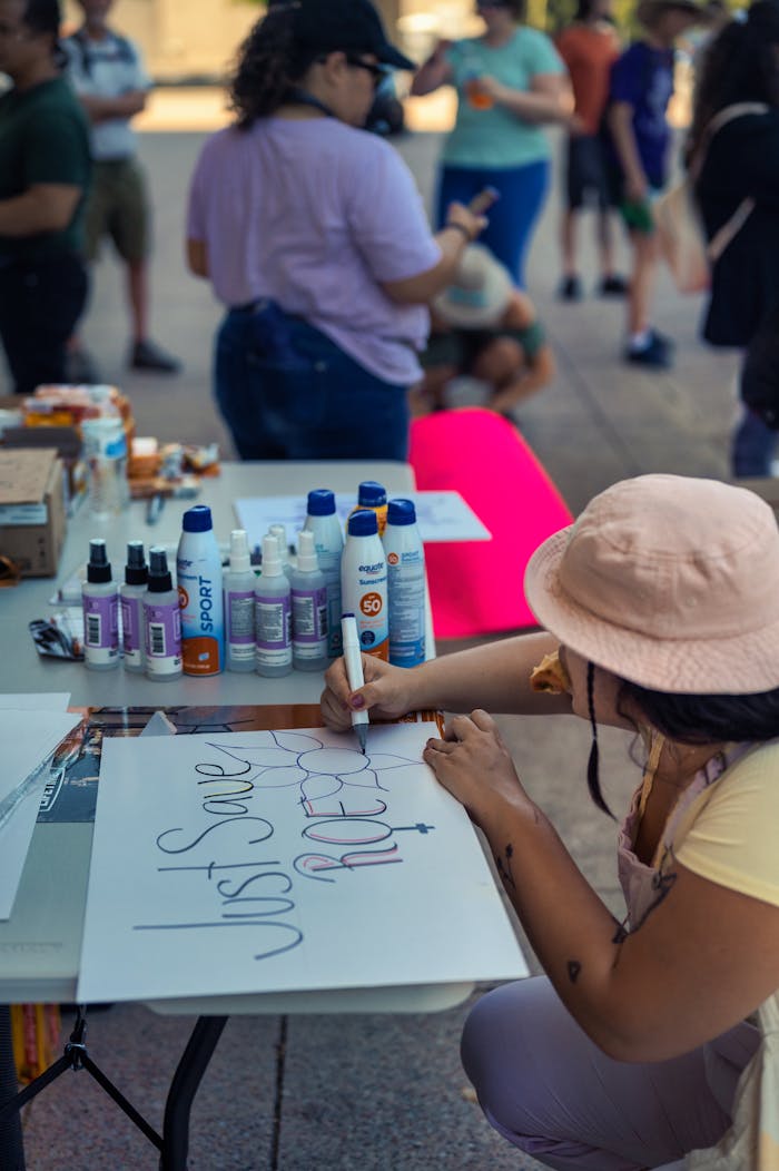 services-03 Woman creating a protest sign at an outdoor gathering.